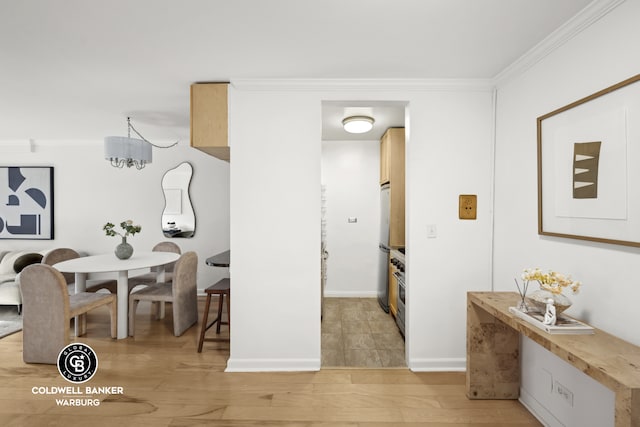 dining room with light wood-style floors, ornamental molding, and baseboards