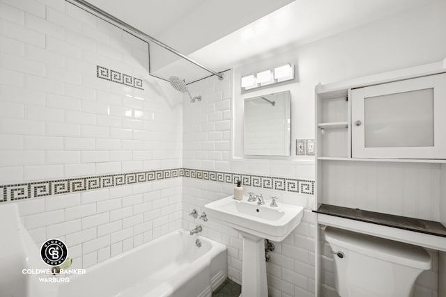 bathroom with washtub / shower combination, tile walls, and toilet