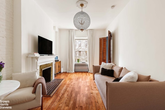 living room featuring a tiled fireplace, radiator heating unit, and light hardwood / wood-style floors