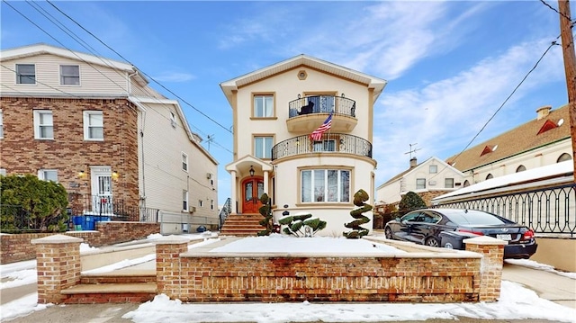 view of front of home with french doors, a balcony, and stucco siding