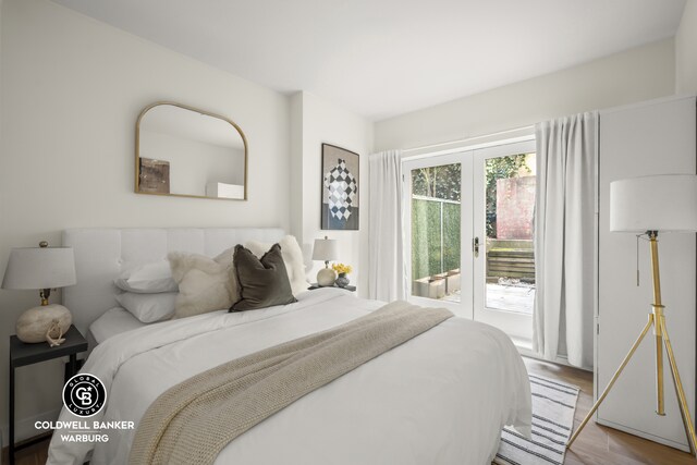 bedroom featuring light hardwood / wood-style flooring, built in desk, access to outside, french doors, and a barn door