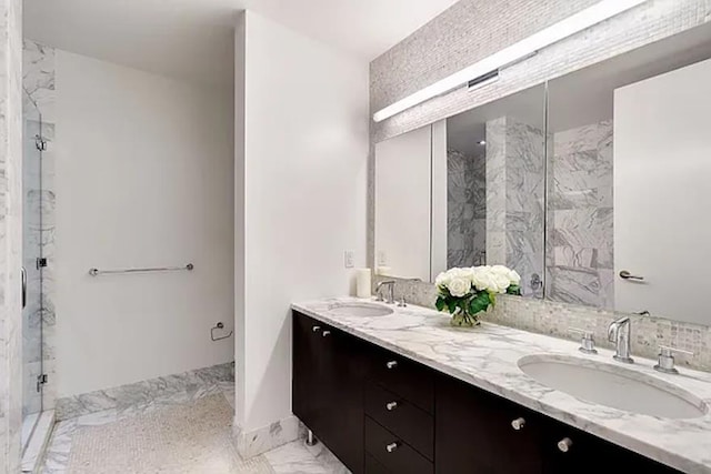 full bathroom featuring double vanity, marble finish floor, a marble finish shower, and a sink