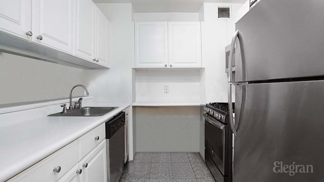 kitchen with stainless steel appliances, white cabinetry, sink, and light tile patterned floors