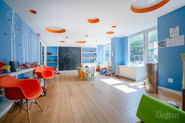 rec room featuring built in shelves and light wood-type flooring