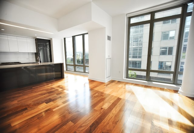 kitchen featuring sink, light hardwood / wood-style flooring, gas cooktop, floor to ceiling windows, and white cabinets