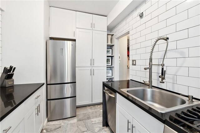 kitchen featuring stainless steel appliances, sink, decorative backsplash, and white cabinets