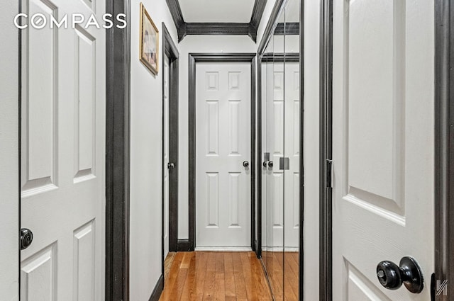 hall with ornamental molding and light wood finished floors