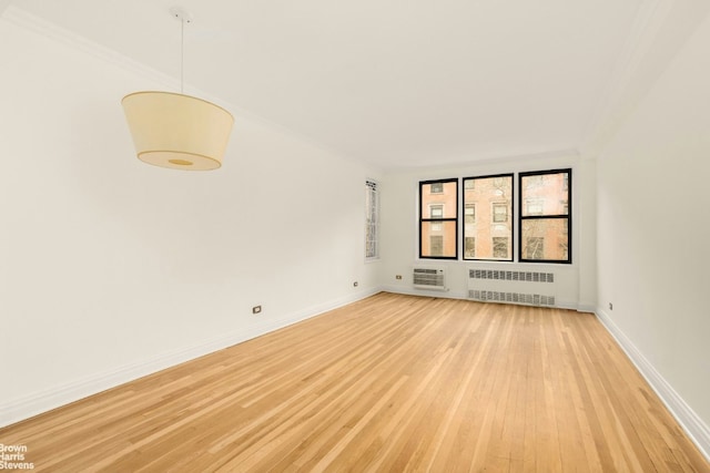 spare room with light wood-style floors, baseboards, ornamental molding, and radiator heating unit