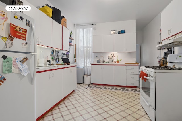 kitchen with white appliances, white cabinets, light floors, light countertops, and under cabinet range hood