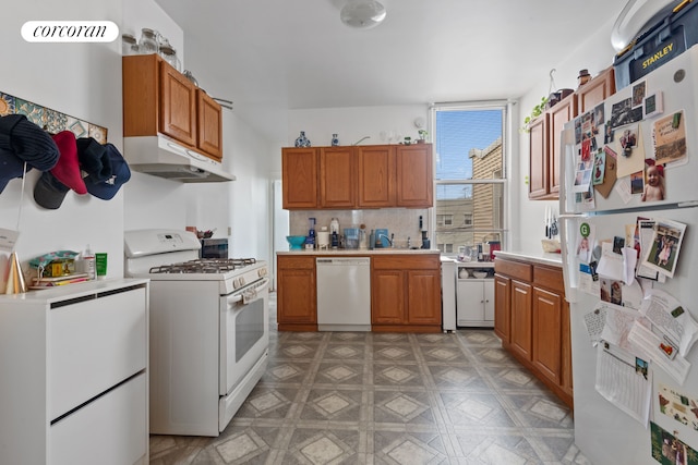 kitchen with light countertops, brown cabinets, under cabinet range hood, and white appliances