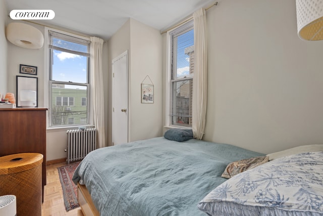 bedroom with radiator heating unit, multiple windows, and visible vents