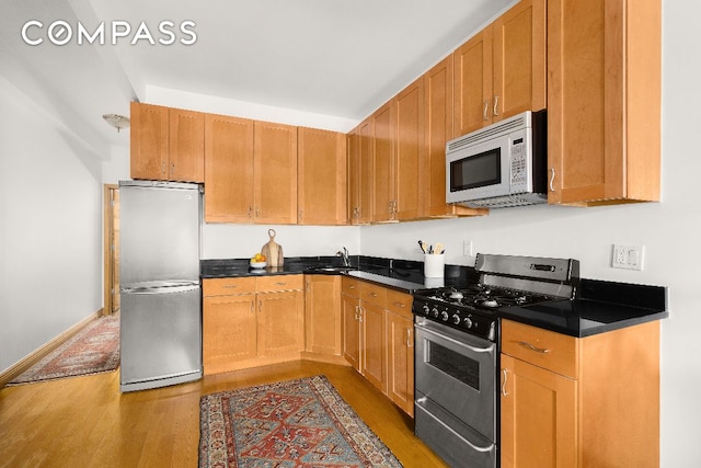 kitchen with appliances with stainless steel finishes, sink, and dark hardwood / wood-style flooring