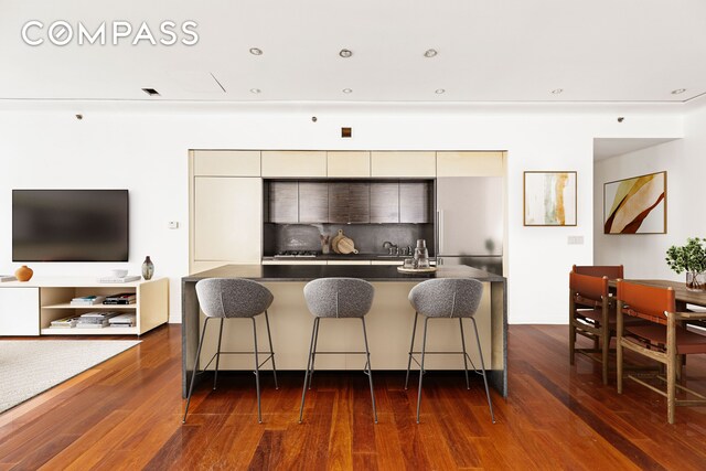 kitchen with a breakfast bar, dark wood finished floors, dark countertops, decorative backsplash, and modern cabinets