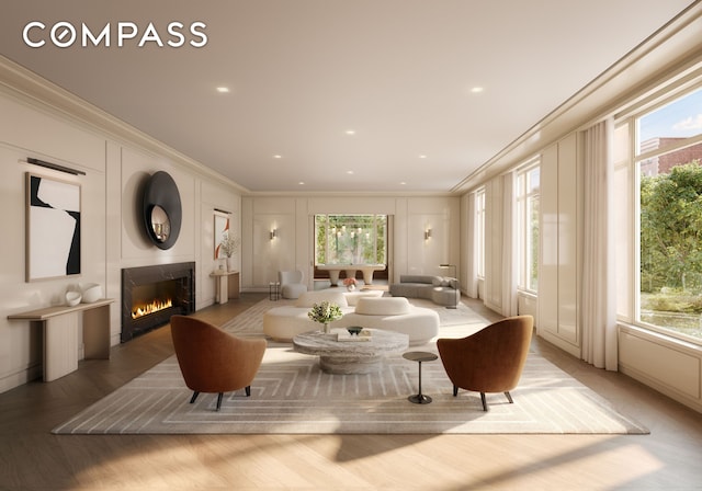living area with a decorative wall, crown molding, healthy amount of natural light, and a warm lit fireplace