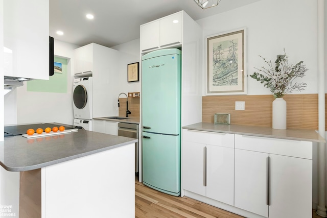 kitchen with light wood-style flooring, black electric cooktop, a sink, white cabinetry, and fridge