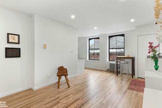 spare room featuring light wood-style floors, recessed lighting, radiator, and baseboards