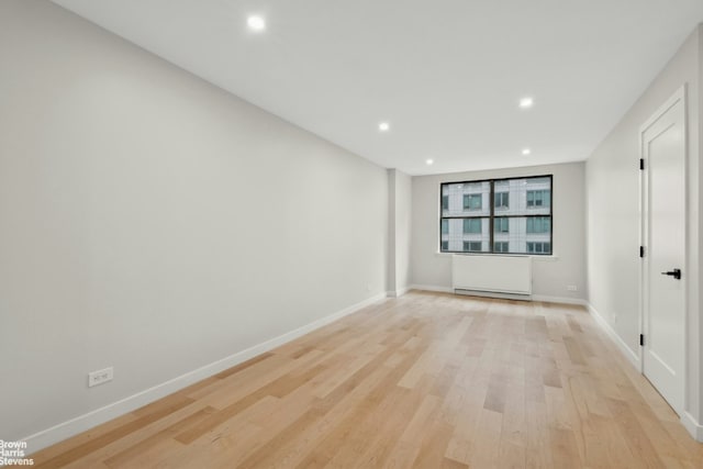 unfurnished room featuring radiator heating unit, recessed lighting, light wood finished floors, and baseboards