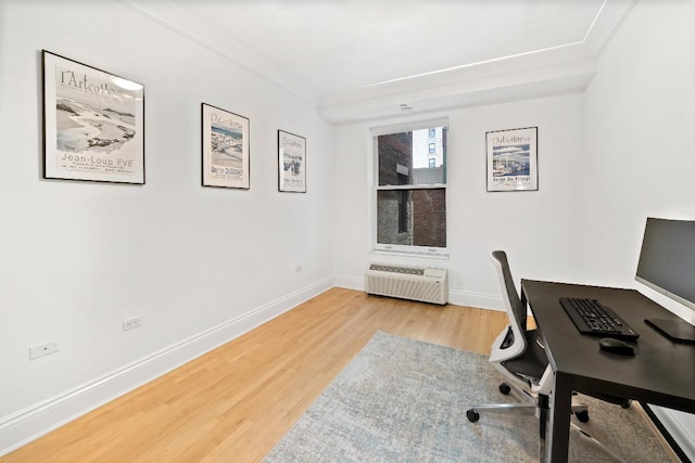 office area featuring crown molding, light hardwood / wood-style floors, and an AC wall unit