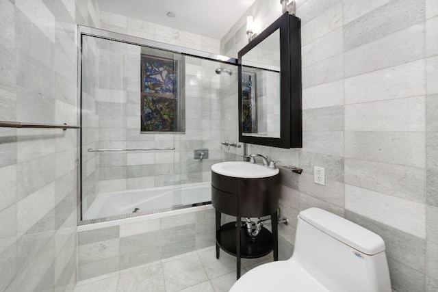 full bathroom featuring sink, tile walls, shower / bath combination with glass door, toilet, and tile patterned floors