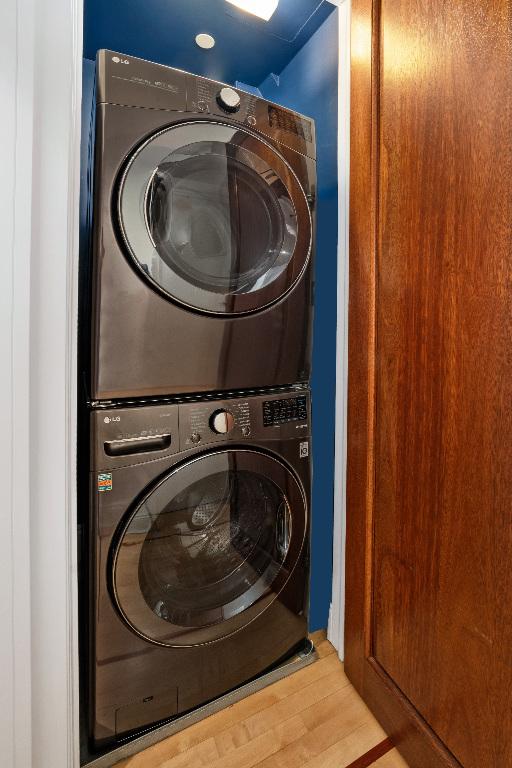 laundry room with hardwood / wood-style floors and stacked washer and clothes dryer