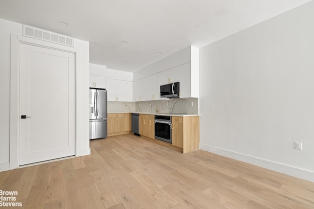 kitchen featuring light wood-style flooring, visible vents, white cabinetry, light countertops, and appliances with stainless steel finishes