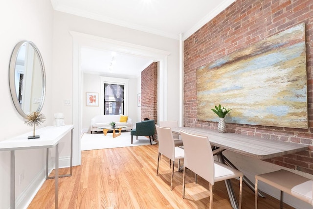 dining area with crown molding, brick wall, and light wood-type flooring