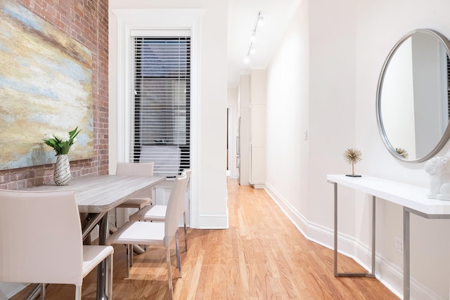 dining space with light wood-style flooring, rail lighting, and baseboards