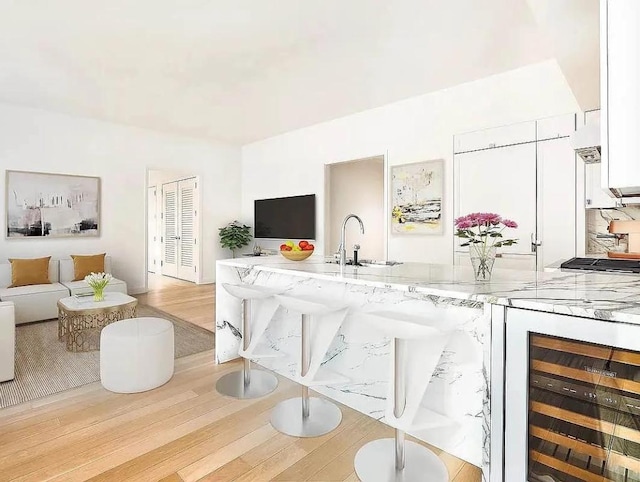 interior space with light stone countertops, white cabinets, sink, light wood-type flooring, and wine cooler