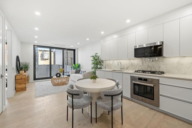 kitchen featuring light hardwood / wood-style flooring, sink, white cabinetry, stainless steel appliances, and tasteful backsplash