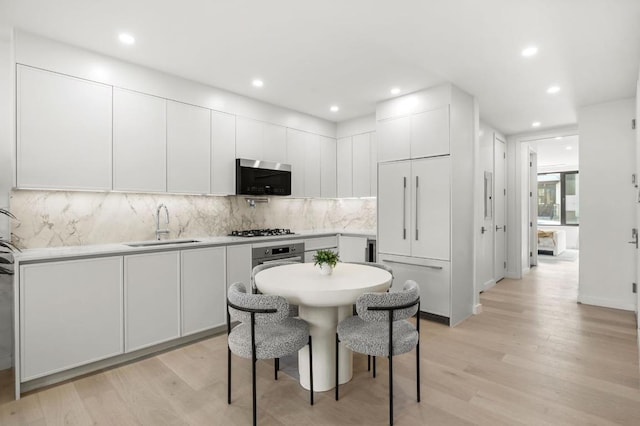 kitchen with light hardwood / wood-style floors, white cabinetry, stainless steel appliances, and sink