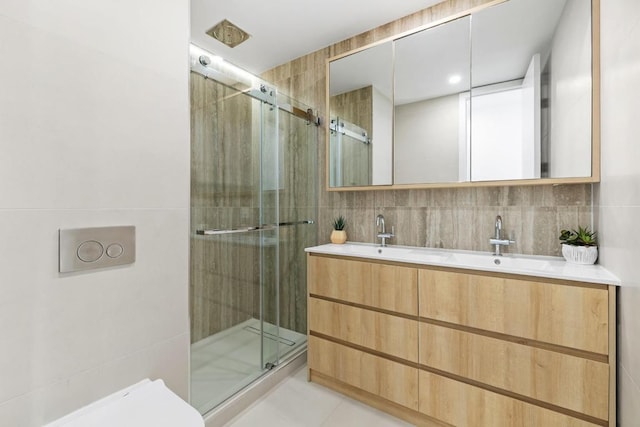 bathroom with a shower with shower door, tile walls, vanity, and backsplash