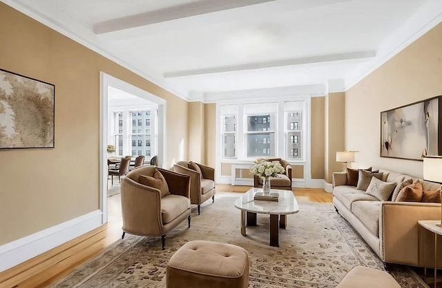 sitting room with baseboards, beamed ceiling, crown molding, and wood finished floors