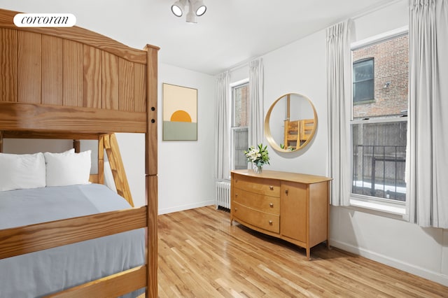bedroom featuring light wood-style floors, radiator, and baseboards