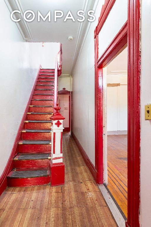 stairs featuring wood-type flooring and ornamental molding