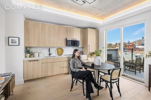 dining area with a raised ceiling and light wood finished floors