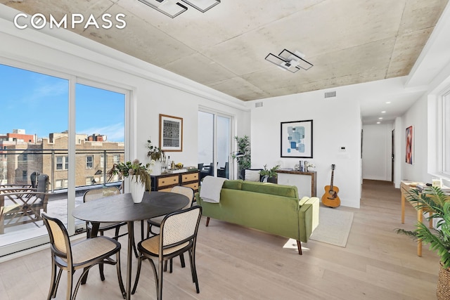 dining area with visible vents, a city view, and light wood-style flooring