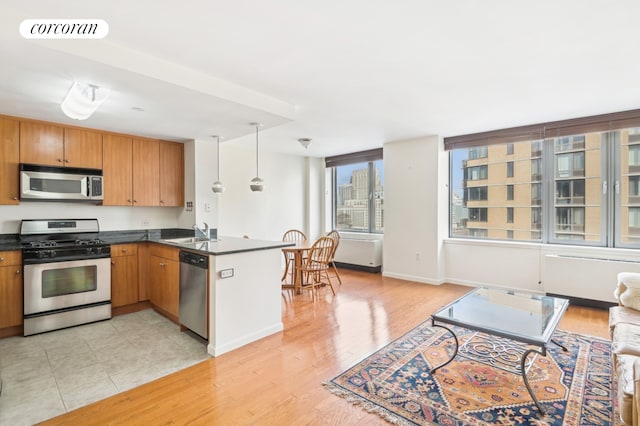 kitchen featuring visible vents, a sink, dark countertops, light wood-style floors, and appliances with stainless steel finishes