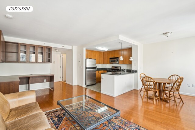 interior space with visible vents, appliances with stainless steel finishes, brown cabinets, glass insert cabinets, and a peninsula