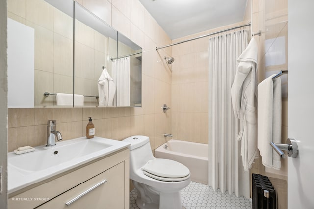 full bath with tile walls, radiator heating unit, shower / bath combo with shower curtain, toilet, and vanity