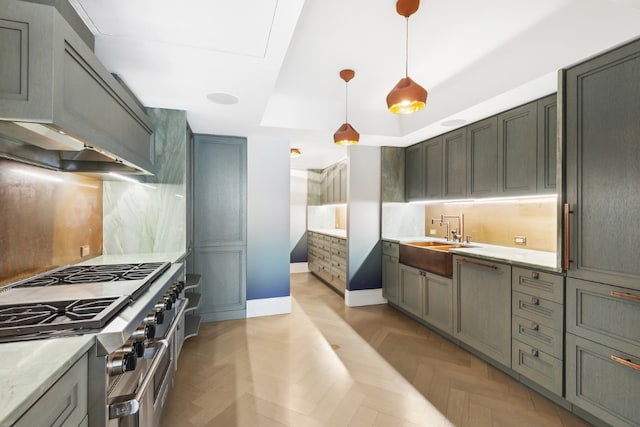 kitchen featuring sink, high end stainless steel range oven, hanging light fixtures, a tray ceiling, and light parquet flooring