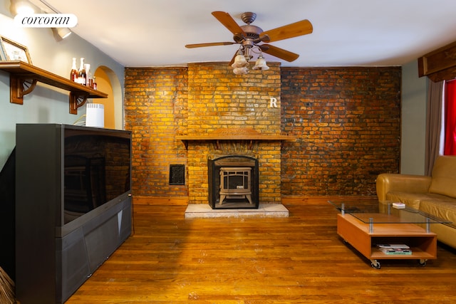 unfurnished living room featuring a wood stove, wood finished floors, ceiling fan, and a fireplace