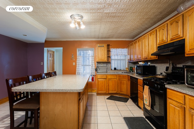kitchen featuring black appliances, an ornate ceiling, a kitchen bar, and under cabinet range hood