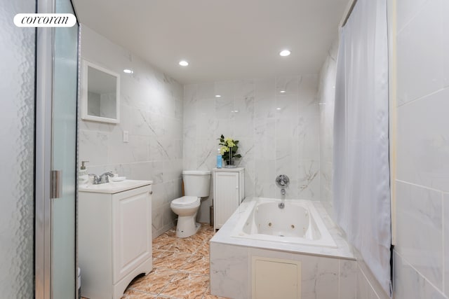 bathroom featuring a tub with jets, vanity, toilet, and tile walls