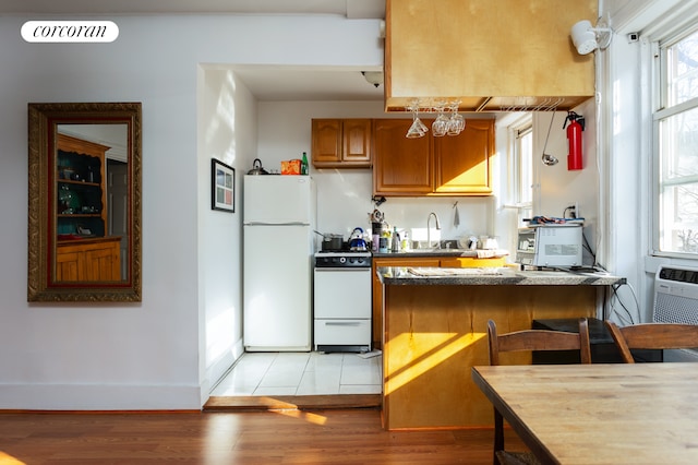 kitchen with a sink, brown cabinetry, visible vents, light wood-style flooring, and white appliances
