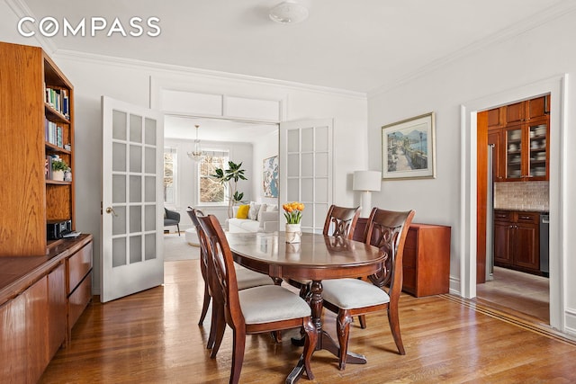 dining room with ornamental molding, a notable chandelier, and wood finished floors