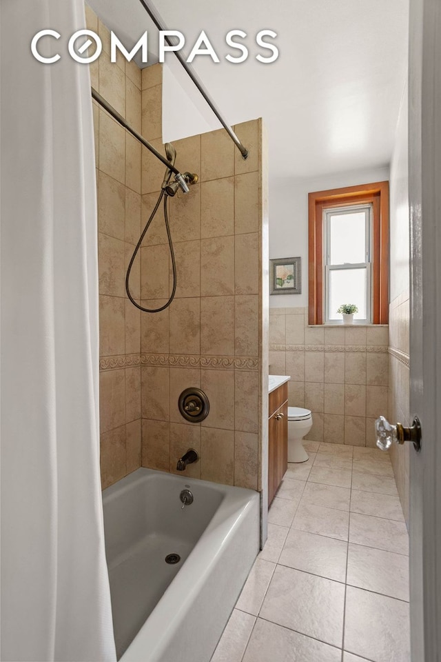 bathroom featuring toilet, tile patterned flooring, shower / bath combo with shower curtain, vanity, and tile walls