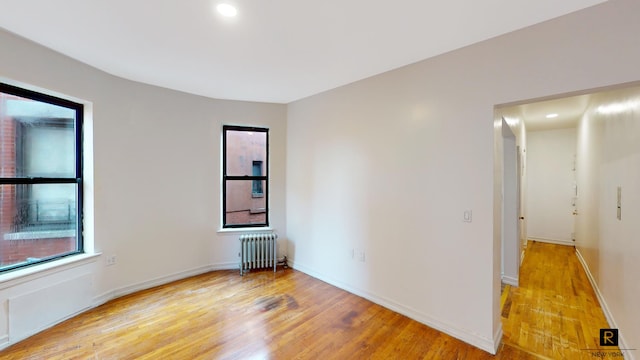 spare room with radiator heating unit, light wood-style floors, recessed lighting, and baseboards