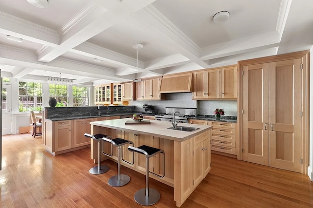 kitchen with a center island with sink, a breakfast bar area, wall chimney range hood, light wood-type flooring, and kitchen peninsula