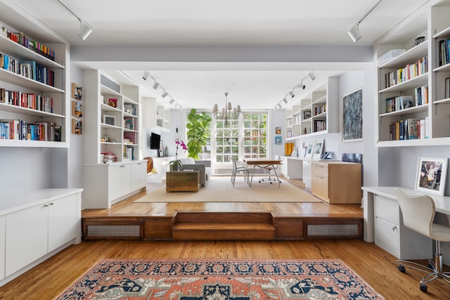 sitting room with track lighting, a chandelier, built in desk, and light wood-type flooring