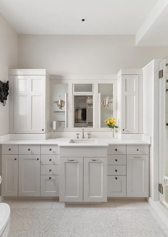 bathroom with toilet, vanity, tile patterned flooring, and a shower with shower door